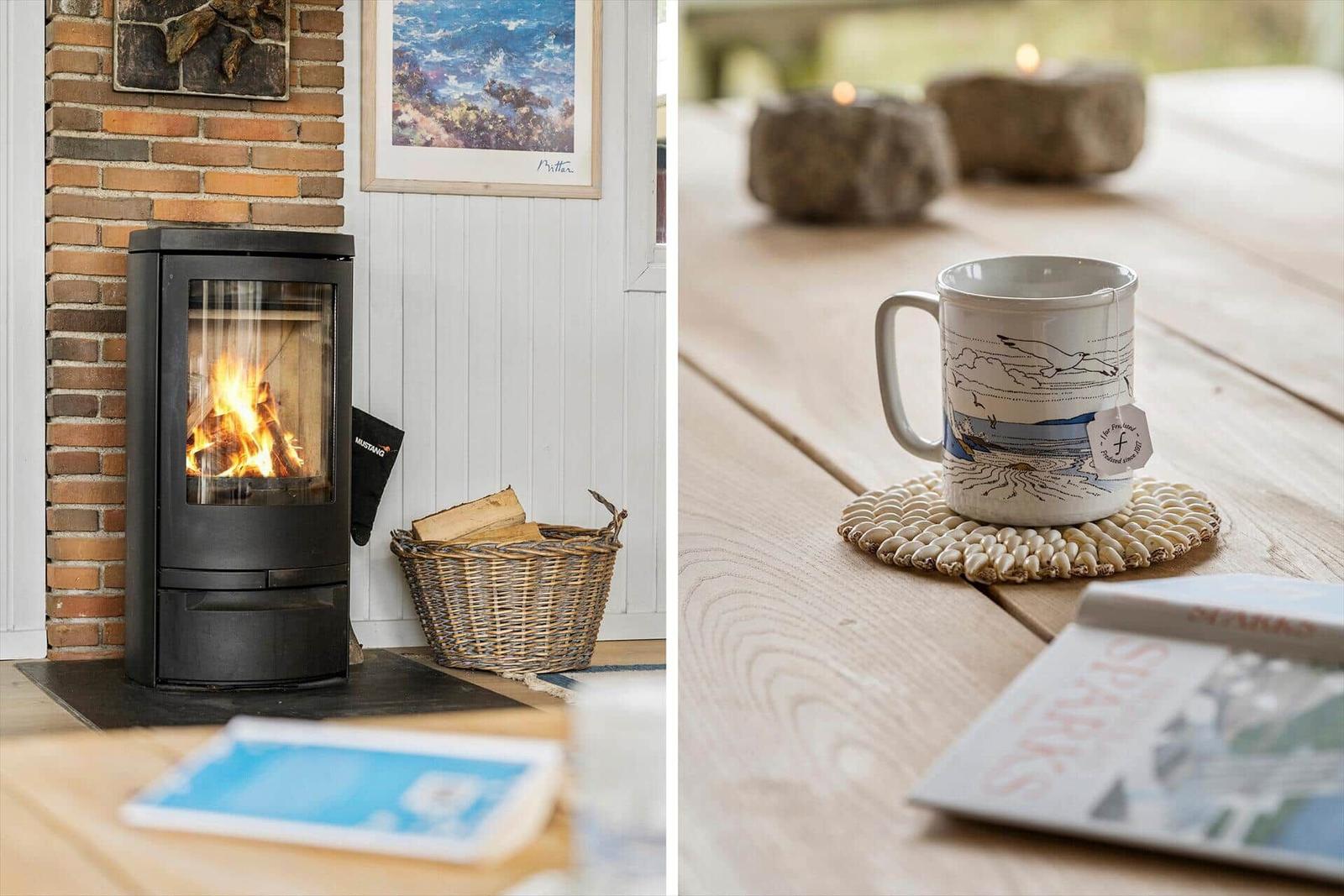 Kamin mit Brennholz und Küchentisch mit Tasse und Kerzen.