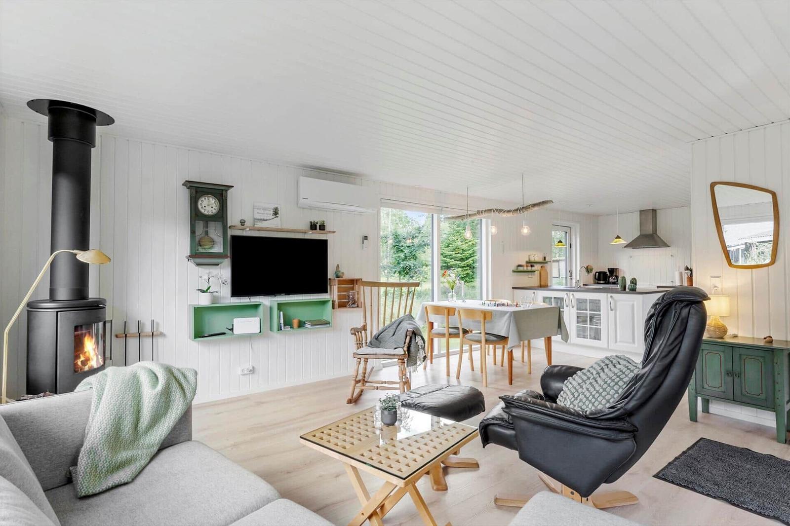 Wohnzimmer mit Kamin, TV und Essbereich. Holzboden und weiße Wände.