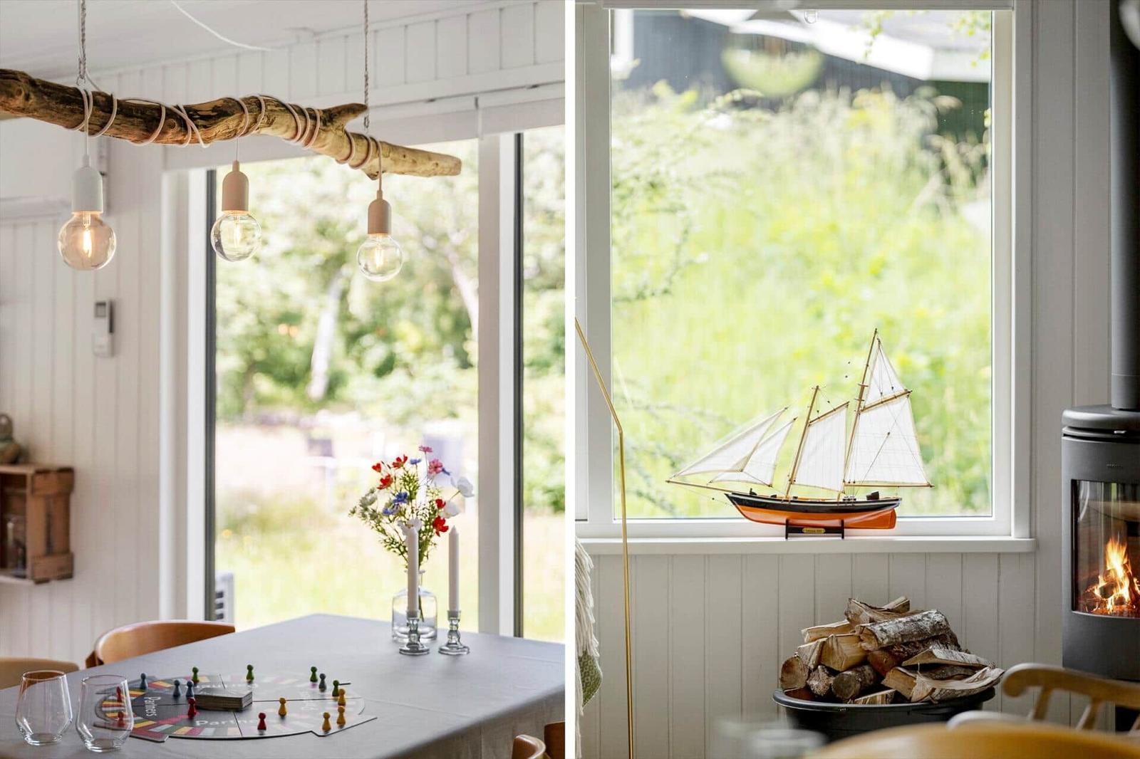 Essbereich mit Tisch, Spiel und Lichtern. Fenster mit Segelschiffmodell und Kamin.