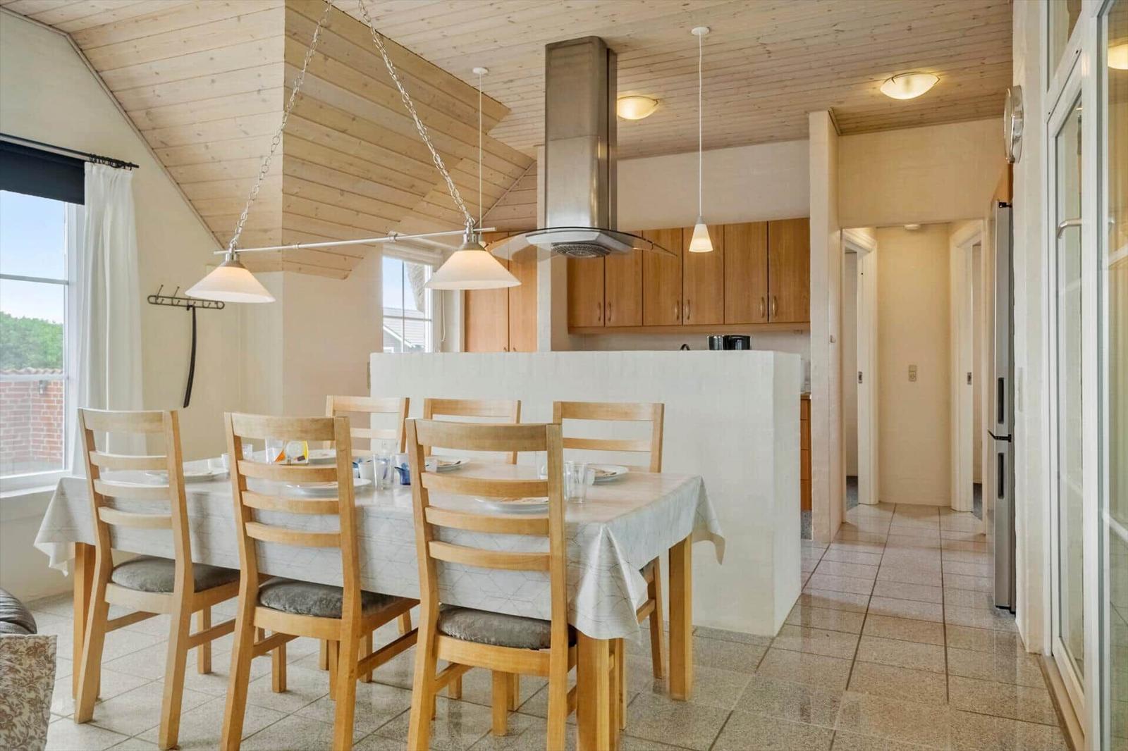 Essbereich mit Holztisch, Stühlen und Küchenbereich mit Holzschränken.