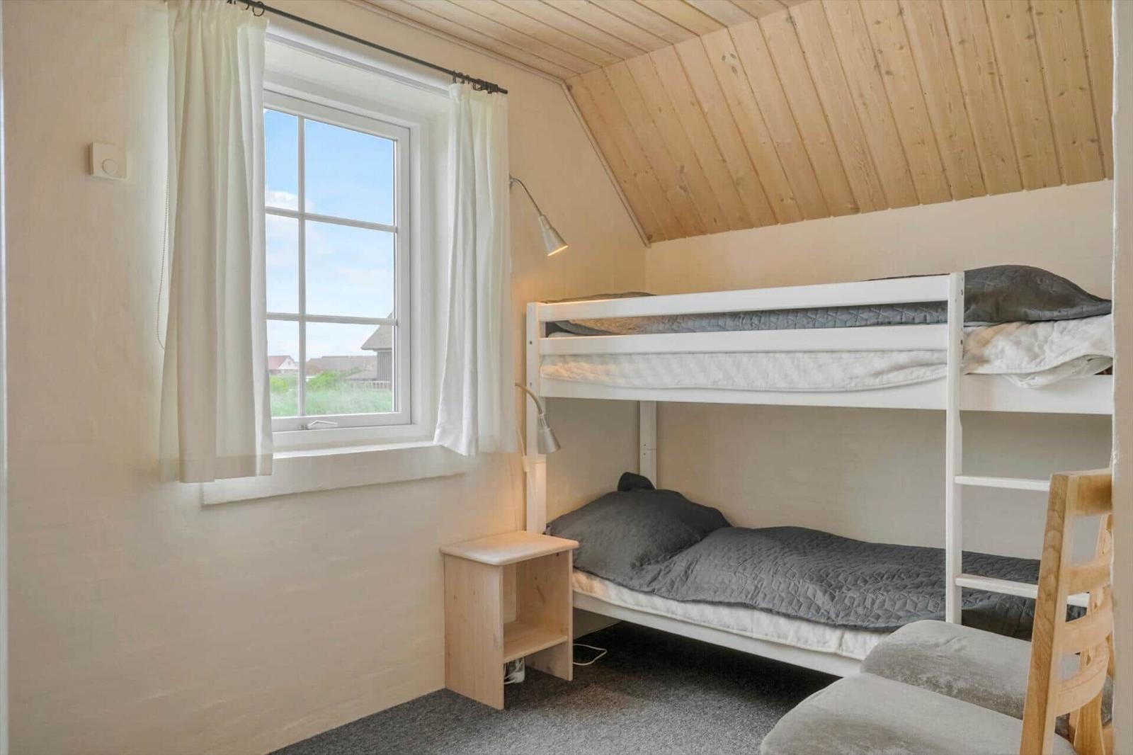 Zimmer mit Doppelstockbett, Fenster und Holzdecke.