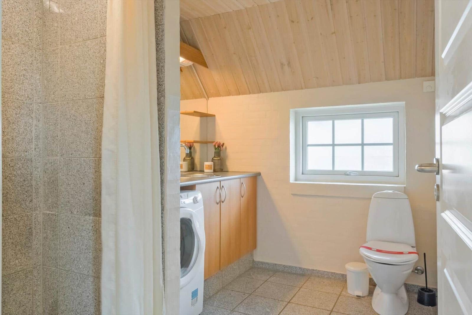 Badezimmer mit Waschmaschine, Toilette und kleinem Fenster