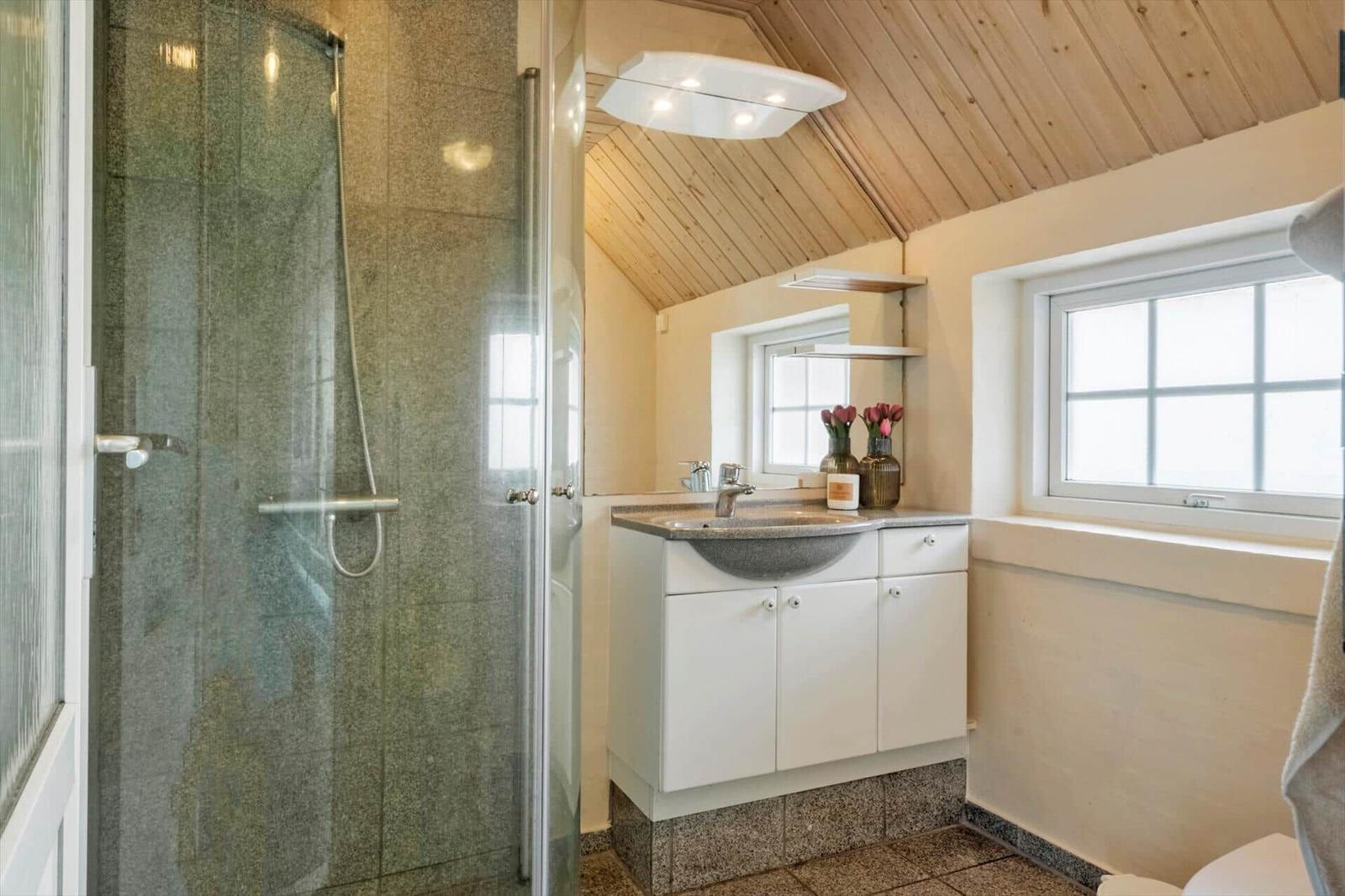 Badezimmer mit Dusche, Waschbecken und Fenster