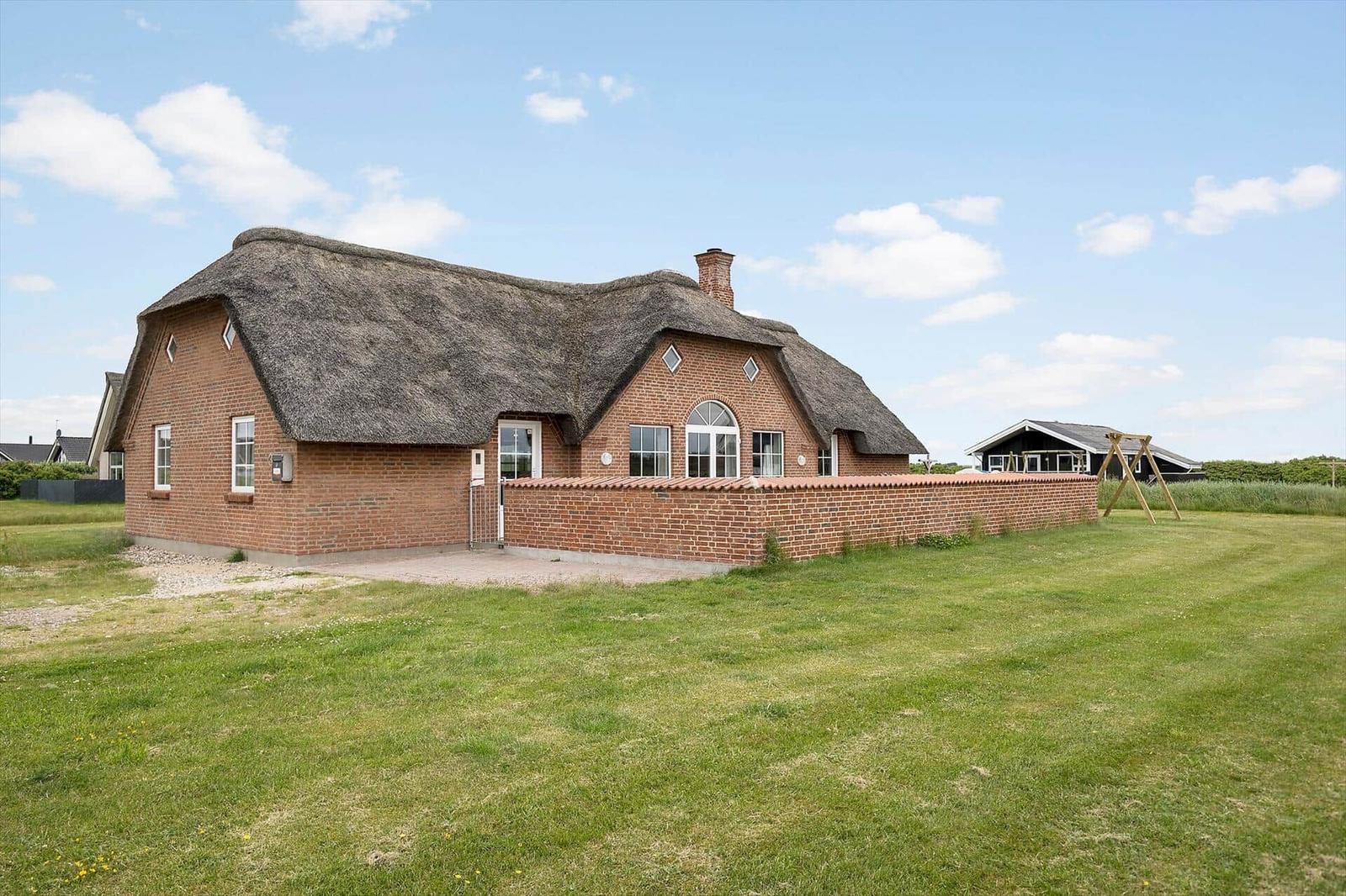 Ein Haus mit strohgedecktem Dach und Backsteinmauer im Freien.