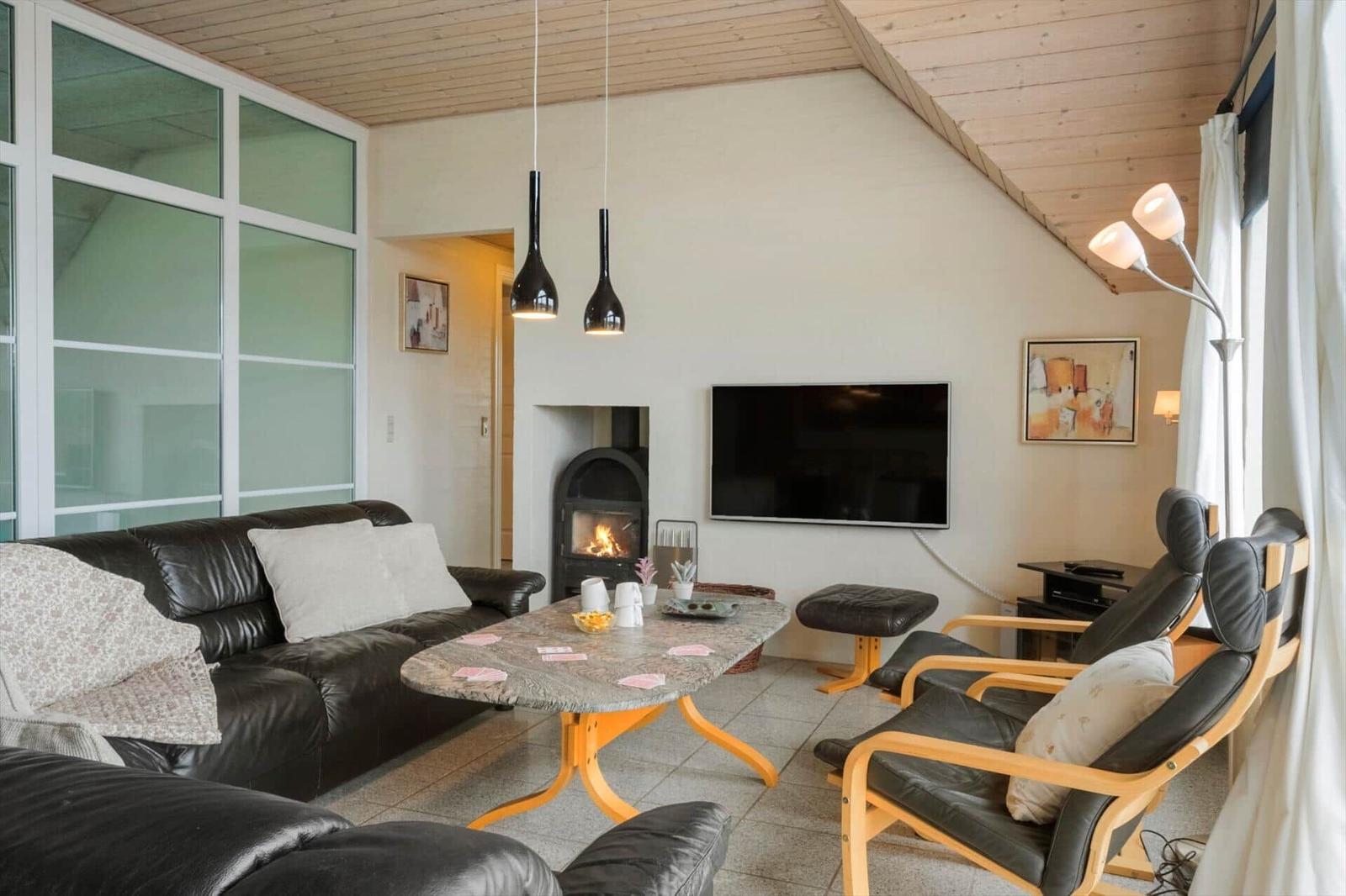 Wohnzimmer mit Sofa, Sessel, Kamin und Fernseher