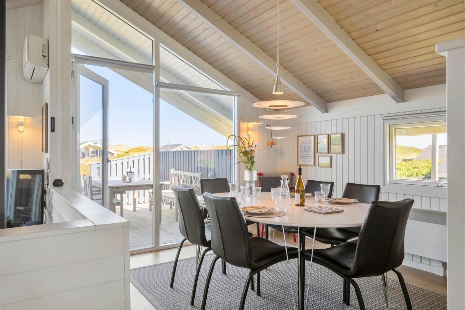 Esszimmer mit runden Tisch, schwarzen Stühlen und Blick auf Terrasse