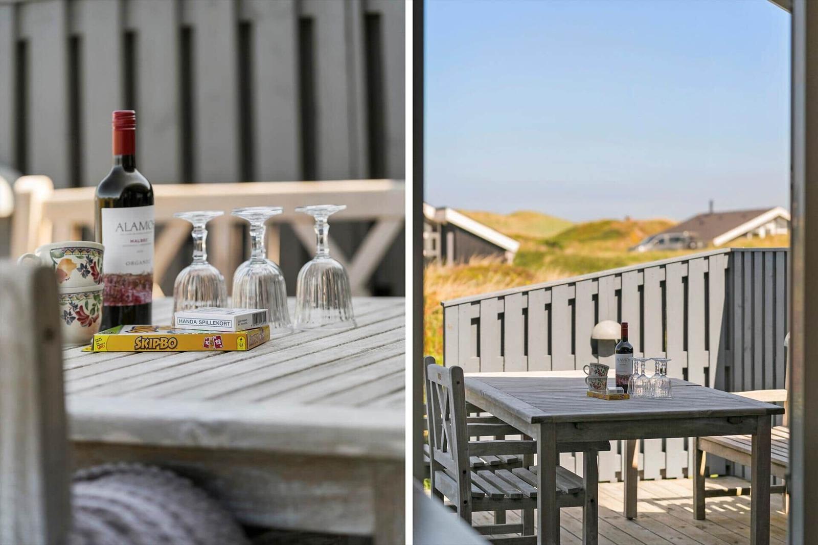 Terrasse mit Tisch, Stühlen und Blick auf Dünenlandschaft.