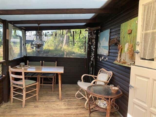 Porch with table, chairs, and seating. View of green landscape.