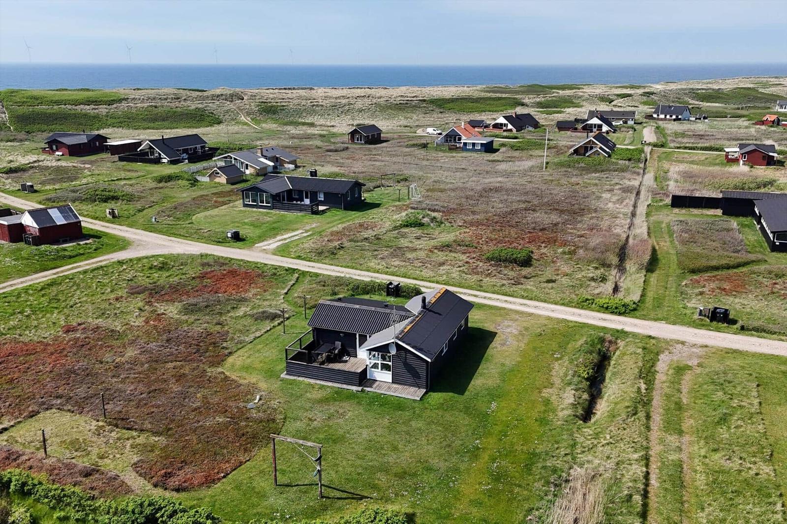 Haus mit Terrasse in einer grünen Landschaft mit Blick auf das Meer.