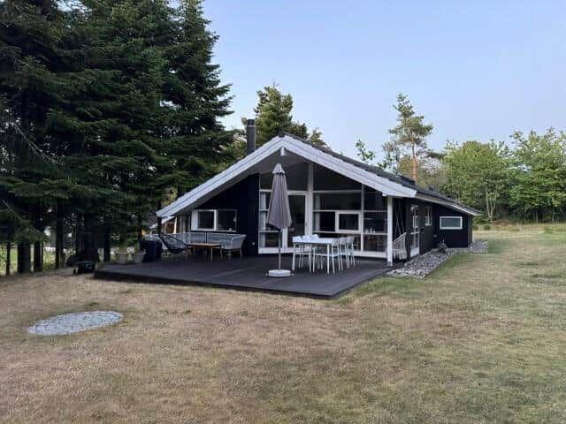 Modern wooden cabin with large terrace and grill area in the green.