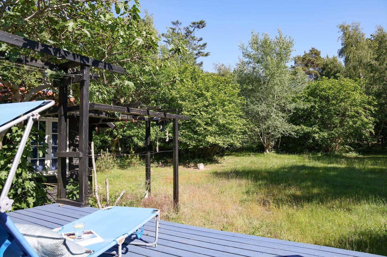 Blue lounge chair on terrace with view of green garden and trees.