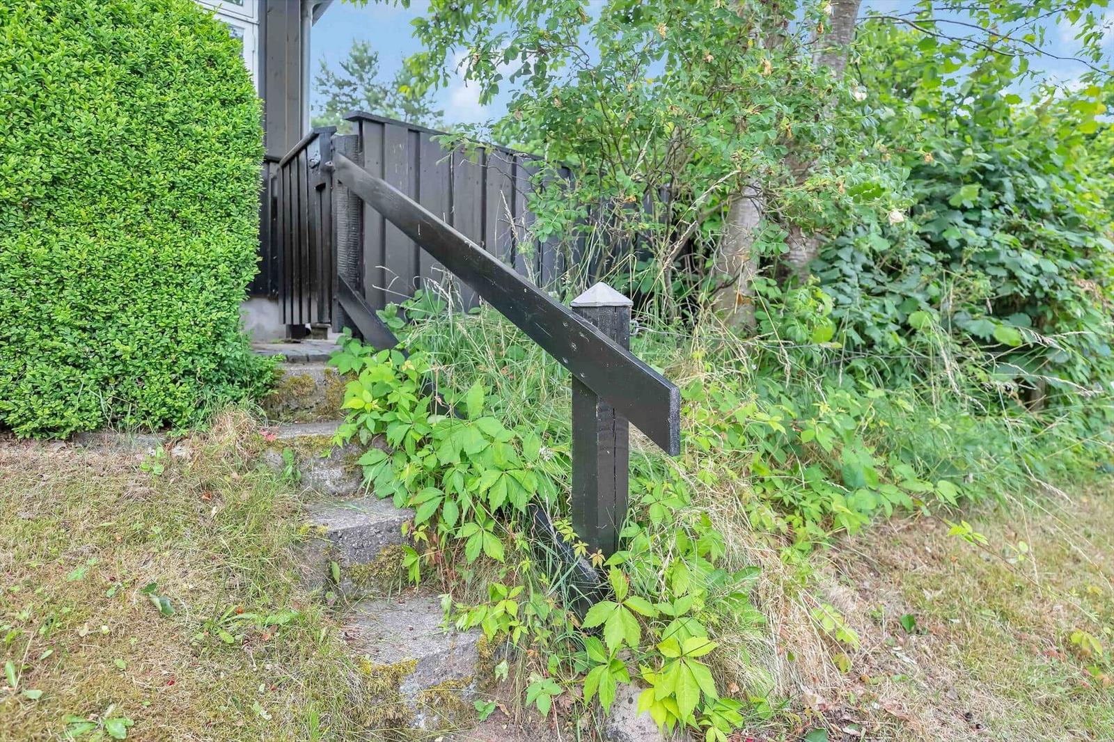 Stone stairs with black handrail in the green garden area.
