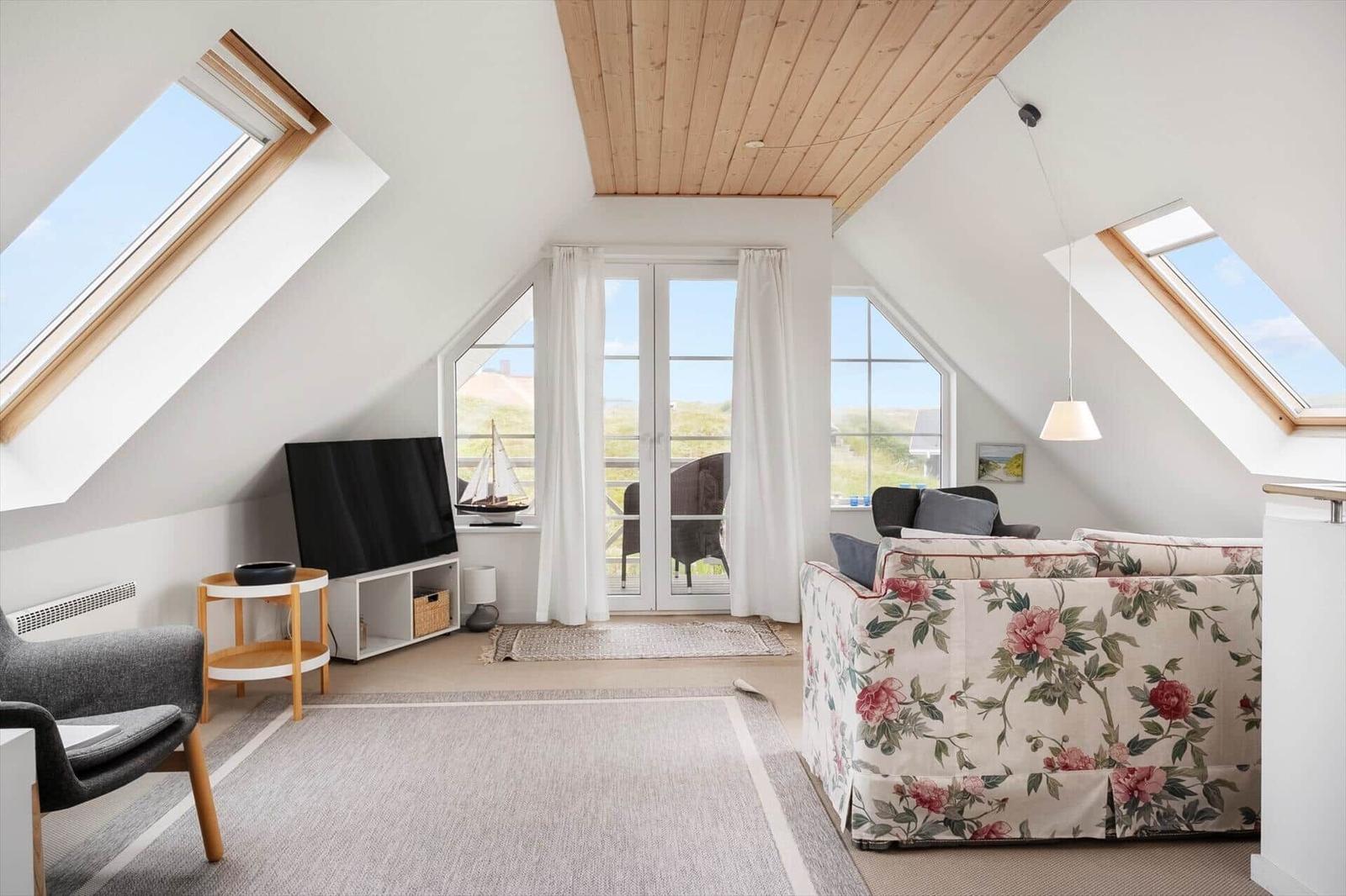 Dachgeschosswohnung mit Fenstern, Sofa und Fernseher