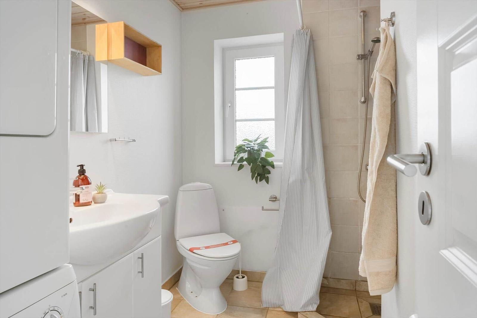 Badezimmer mit Toilette, Dusche, Waschbecken und Fenster
