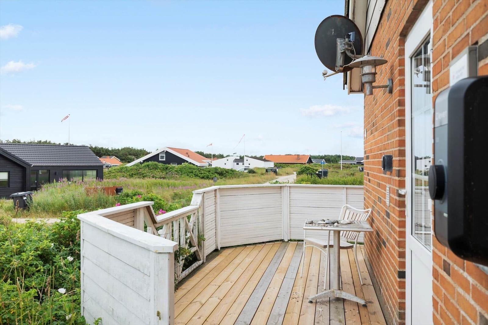 Terrasse mit Tisch und Stühlen, Blick auf Grünflächen und Häuser