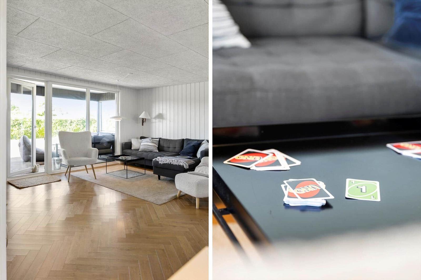 Wohnzimmer mit Sofa, Sessel und Holzboden. Tisch mit Uno-Karten.