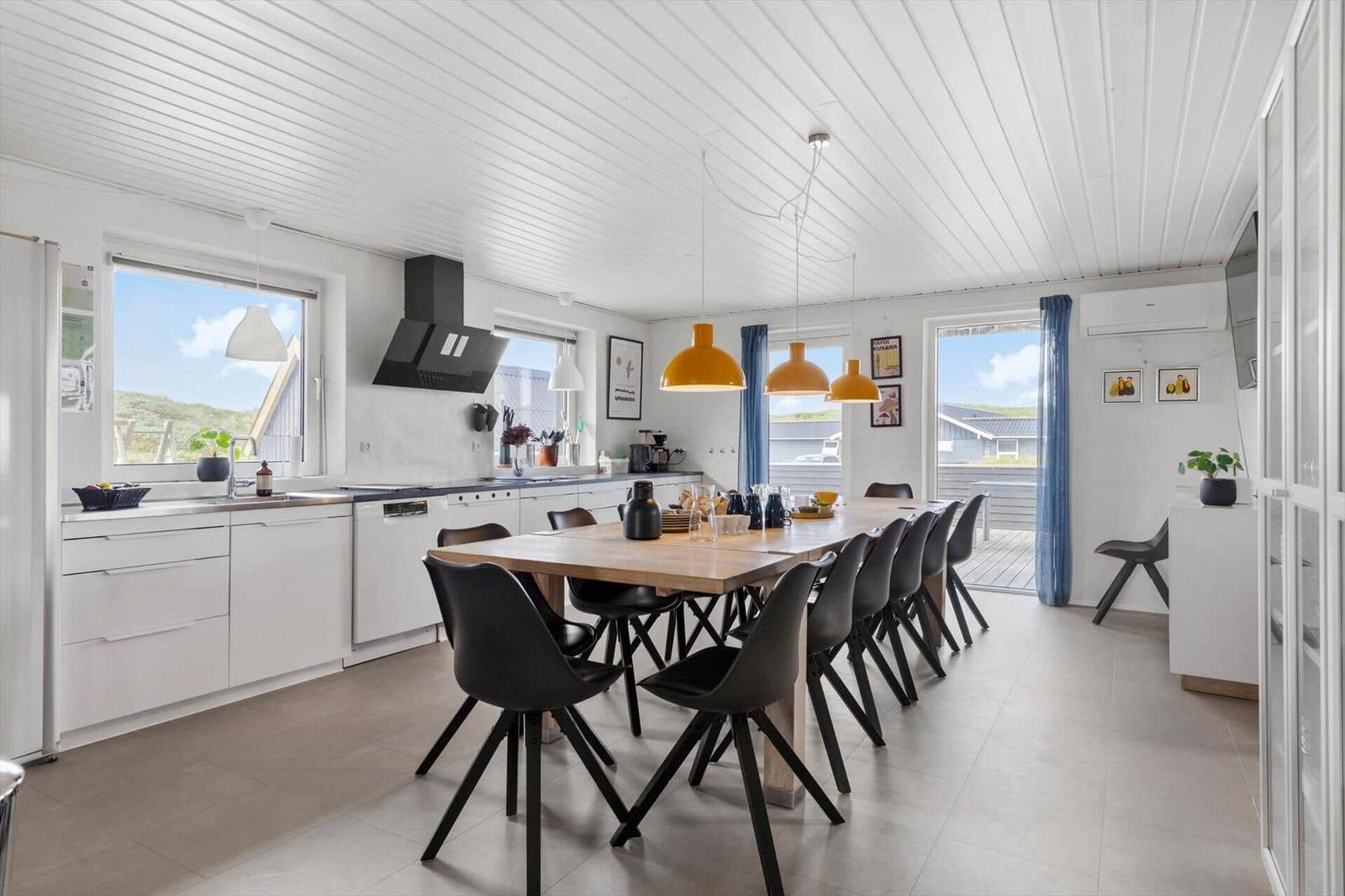 Kitchen and dining area with wooden table, black chairs, and windows for views.