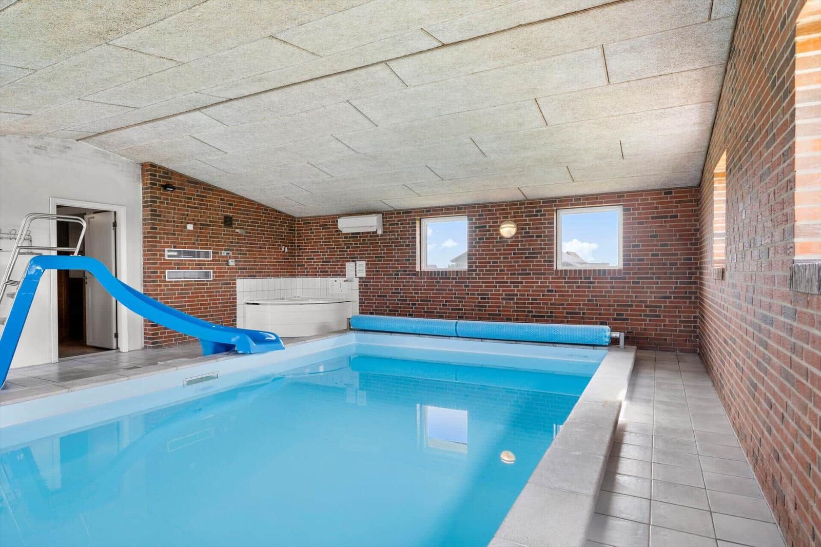 Indoor pool with blue slide and hot tub
