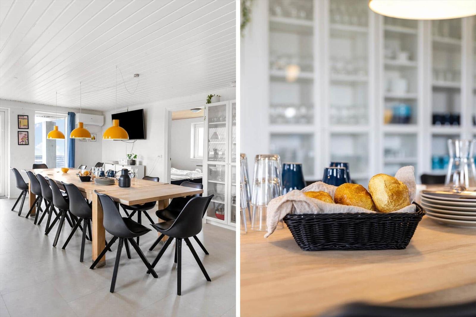 Dining room with long wooden table and black chairs. Kitchen area with bread basket and glass cabinets.