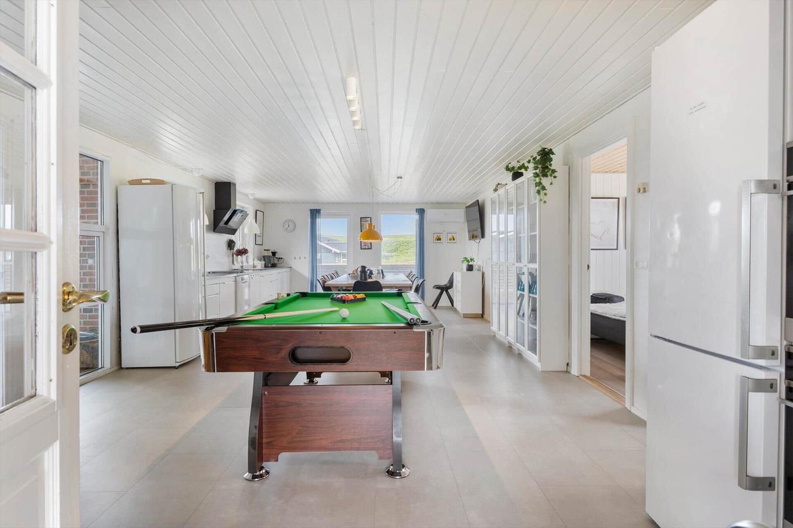 Pool table in center, kitchen and bedroom in background.