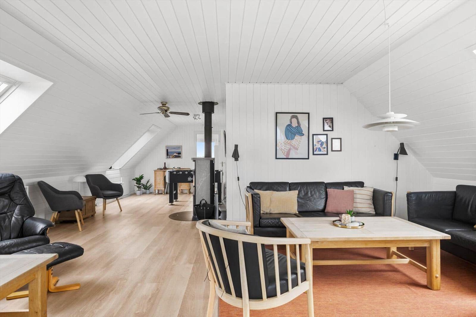 Living room with black sofa, wooden table, and sloped ceiling