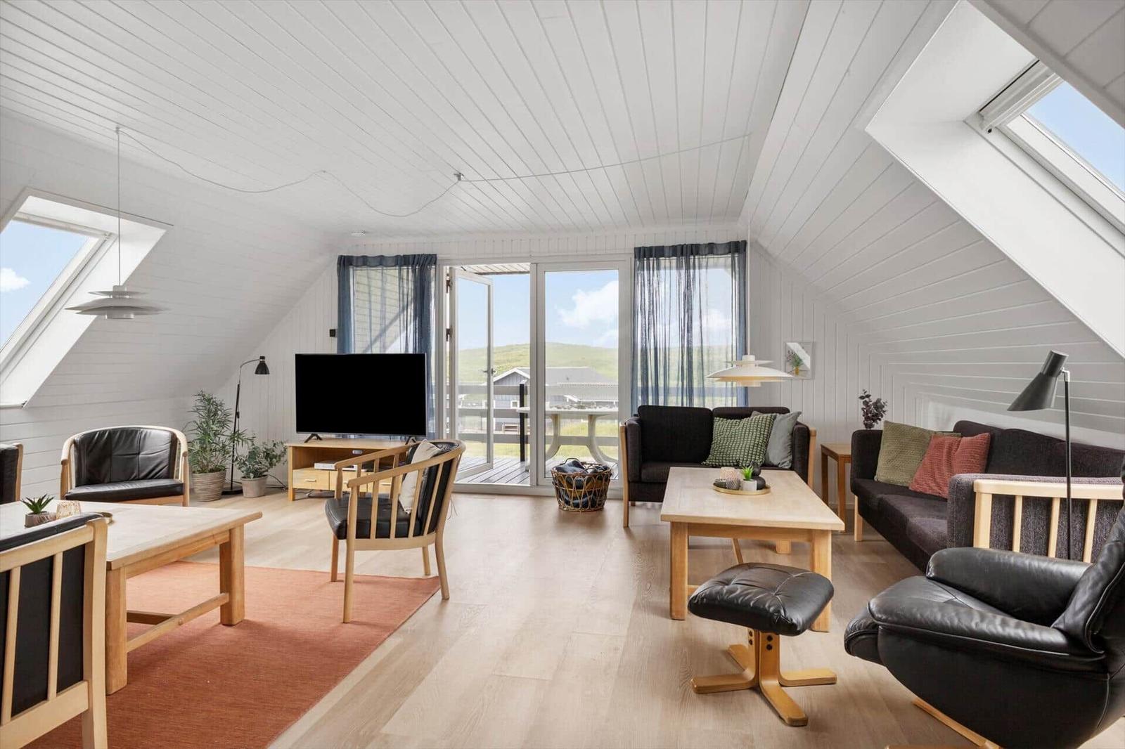 Living room with wooden floor, windows and sliding doors. Furniture made of wood and leather.