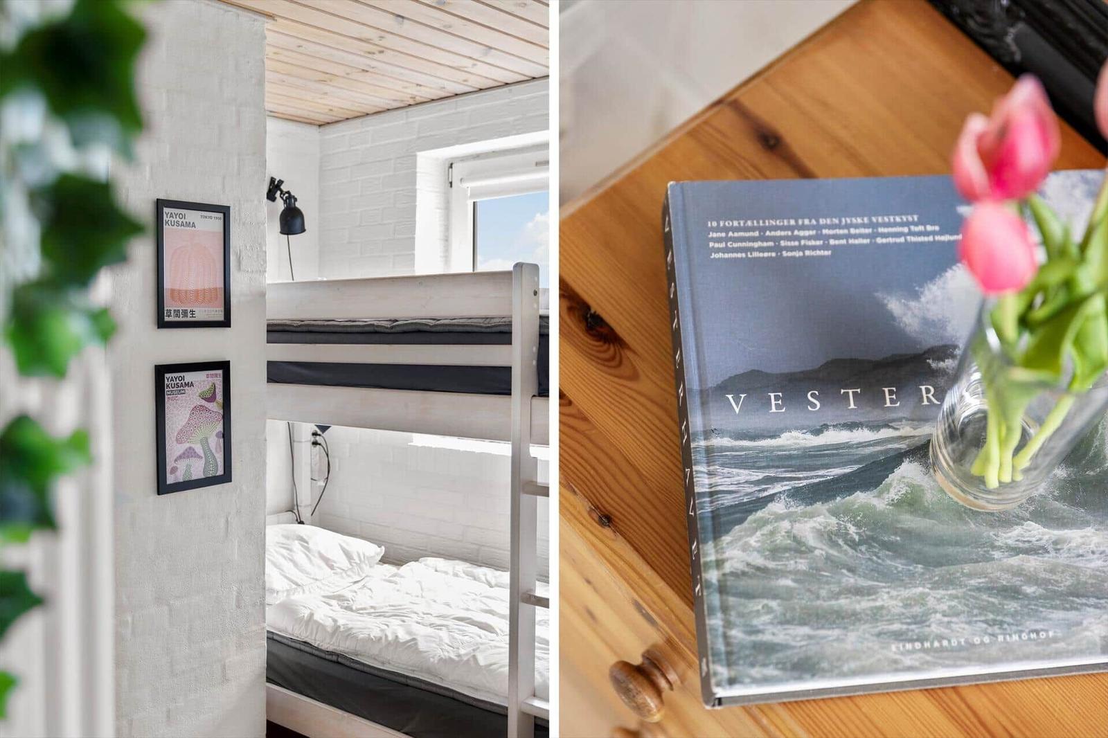 Room with bunk beds and wall art. Wooden table with book and tulips.