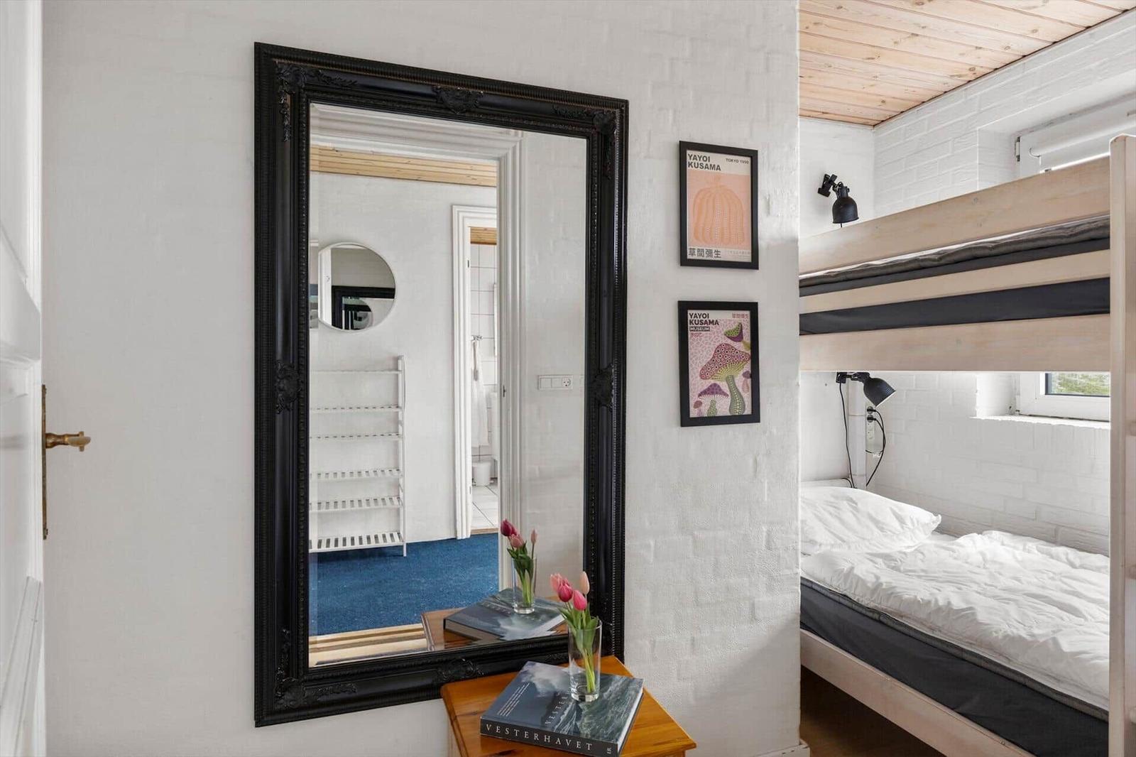 Bedroom with bunk bed, mirror, and wall art. Blue carpet visible in mirror.