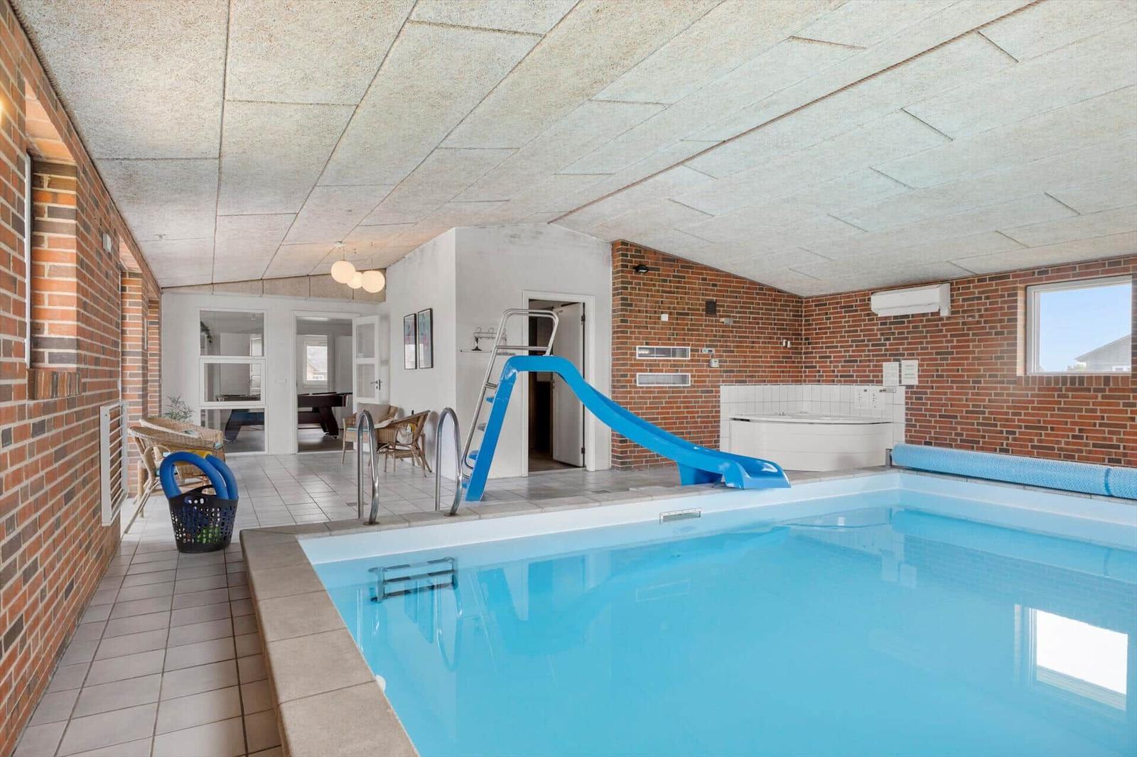 Indoor pool with blue slide and hot tub. Access via stairs.