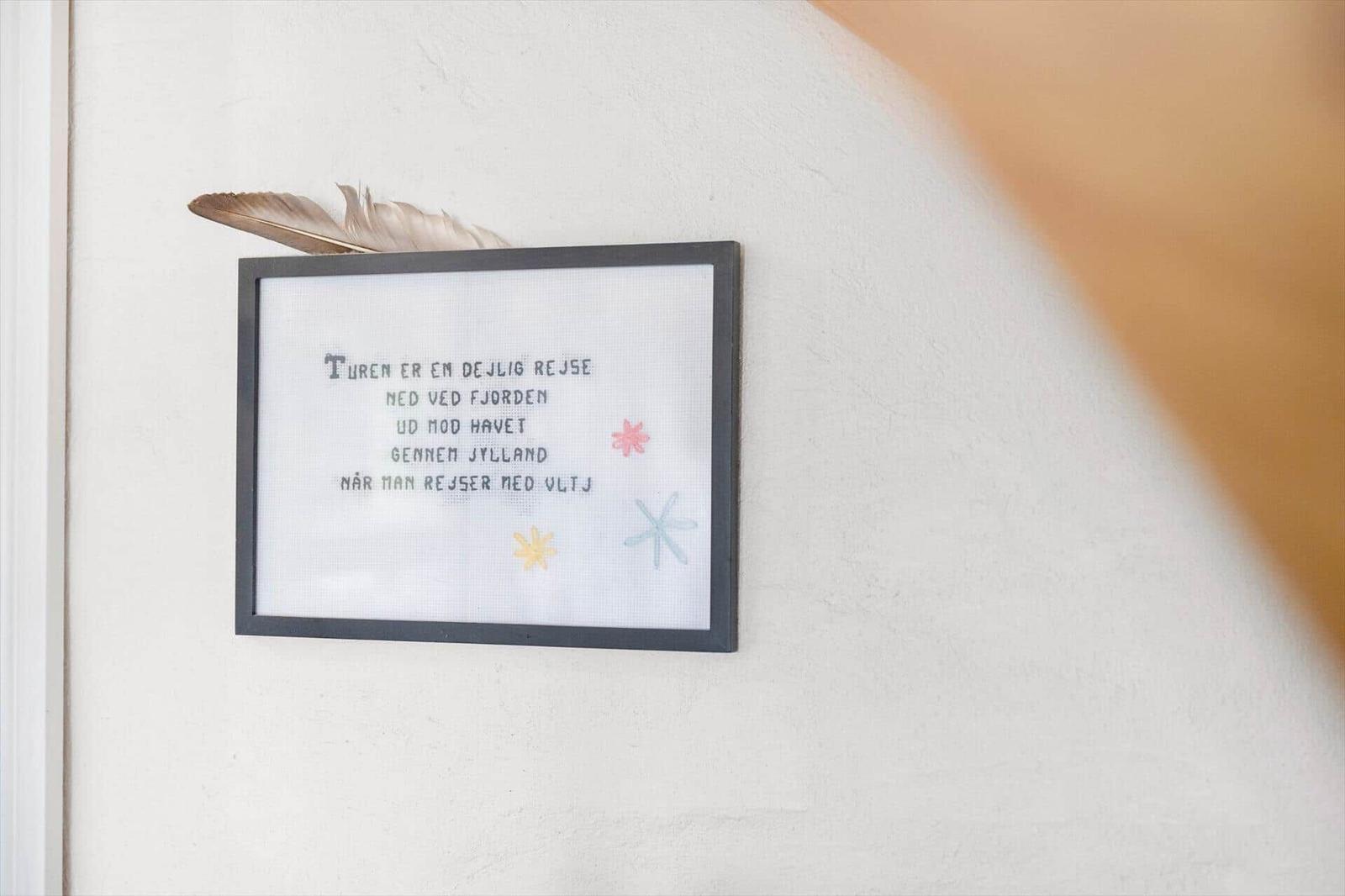 A framed sign with text and feathers on the wall.