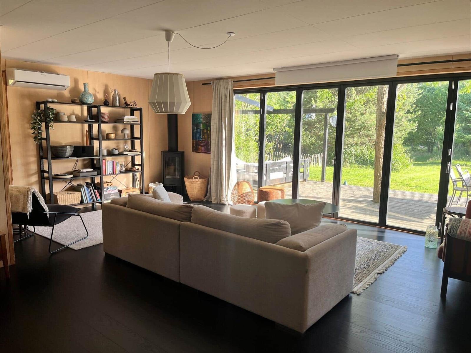 Wohnzimmer mit Sofa, Bücherregal und Glasfront zum Garten.