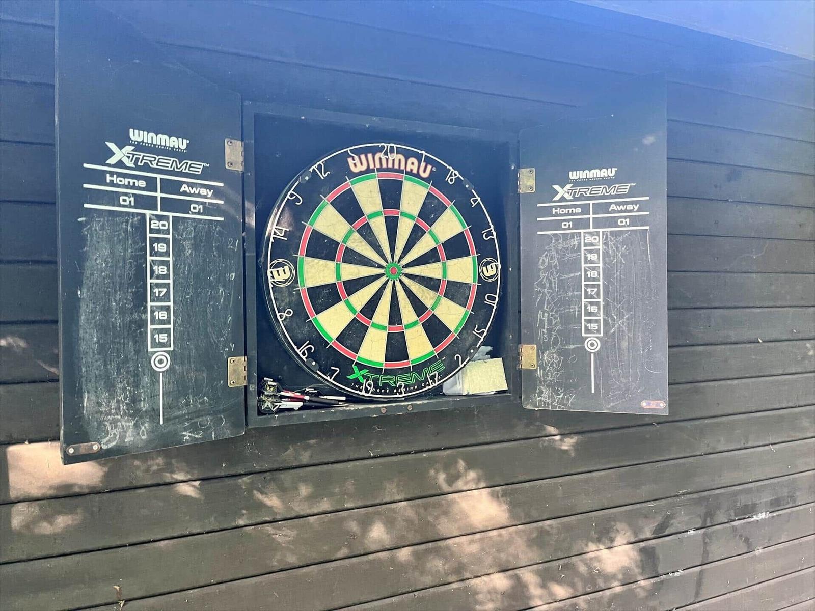 Dartscheibe mit Tafeln an Wand montiert, Darts in Halterung