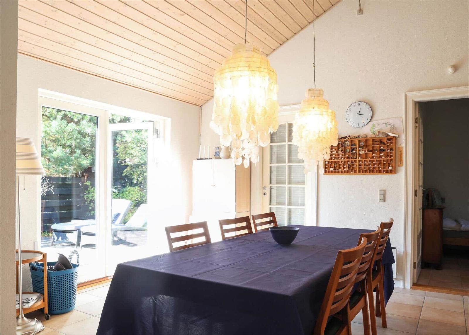 Esszimmer mit Holztisch, Stühlen und Schalentischlampen. Durchgang zur Schlafzimmer.
