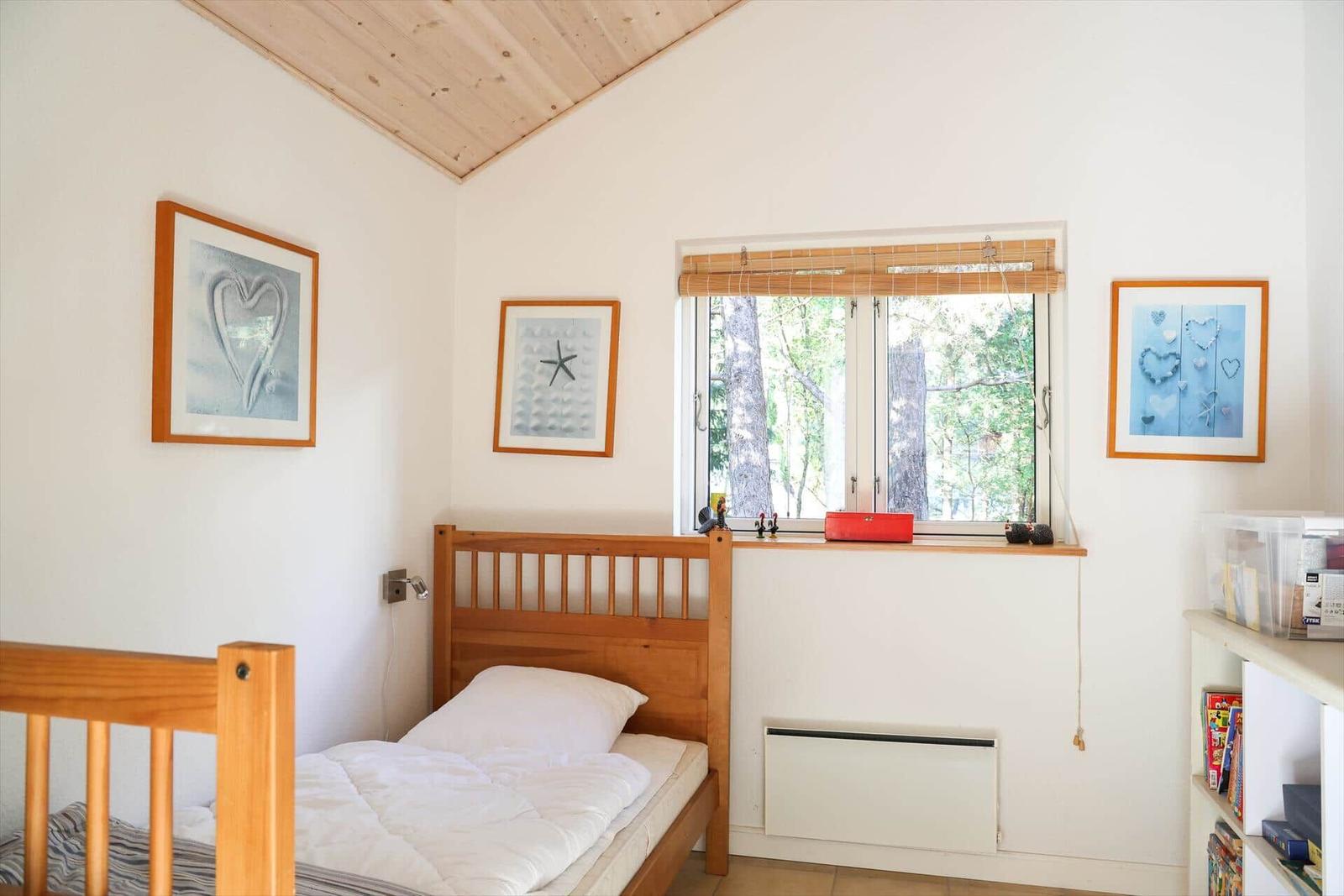 Ein Schlafzimmer mit Holzbett, Fenster und Wandbildern.