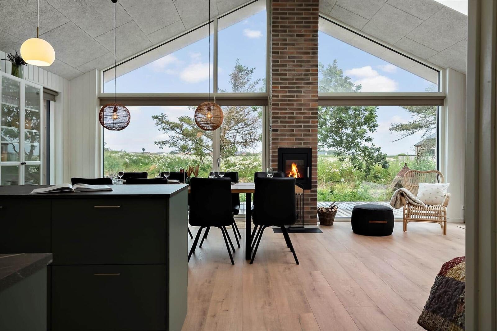 Moderne Küche mit Essbereich, Kamin und großem Fensterblick auf Grünland.