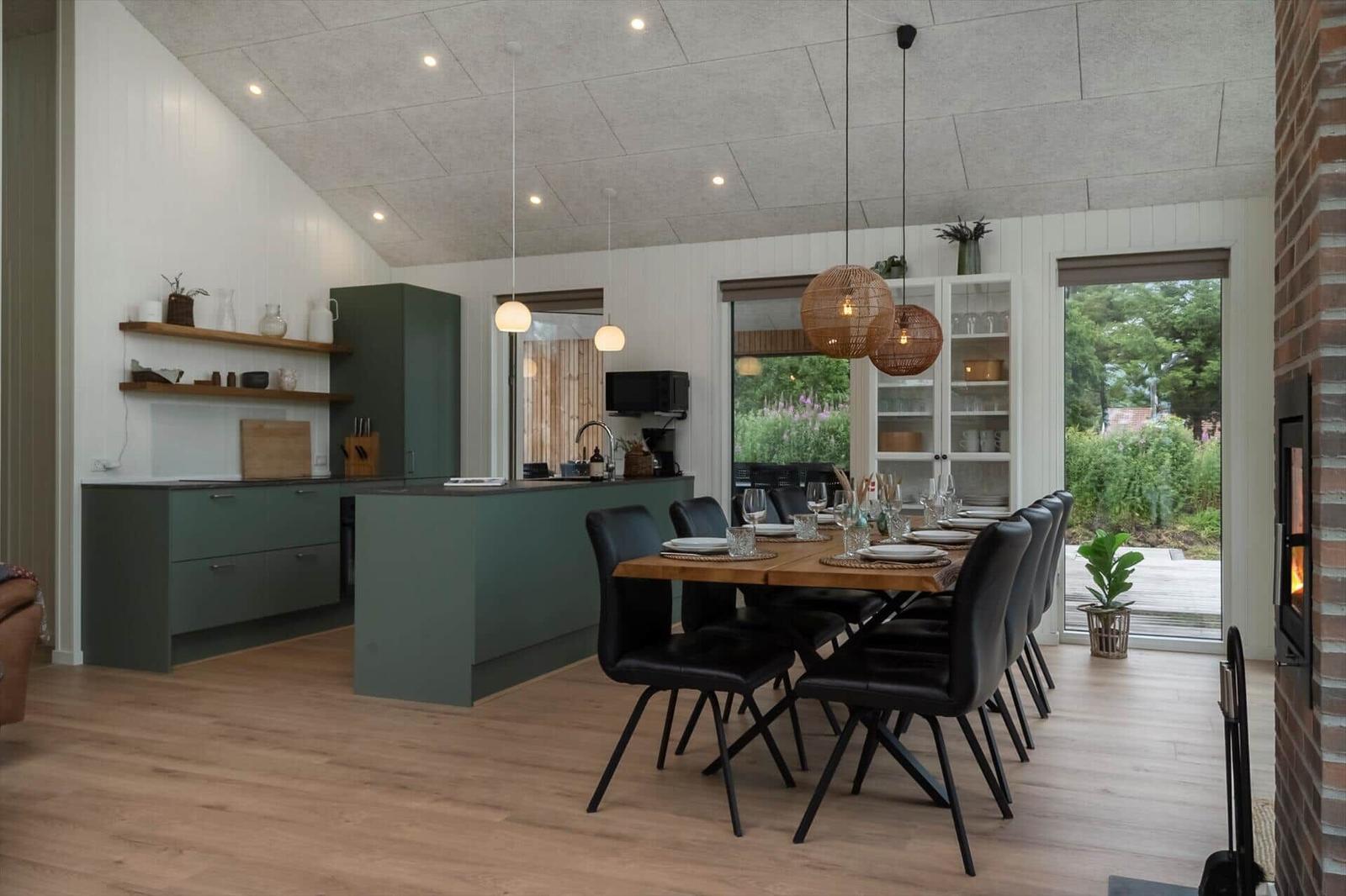 Küche und Essbereich mit Holztisch, schwarzen Stühlen und Kamin