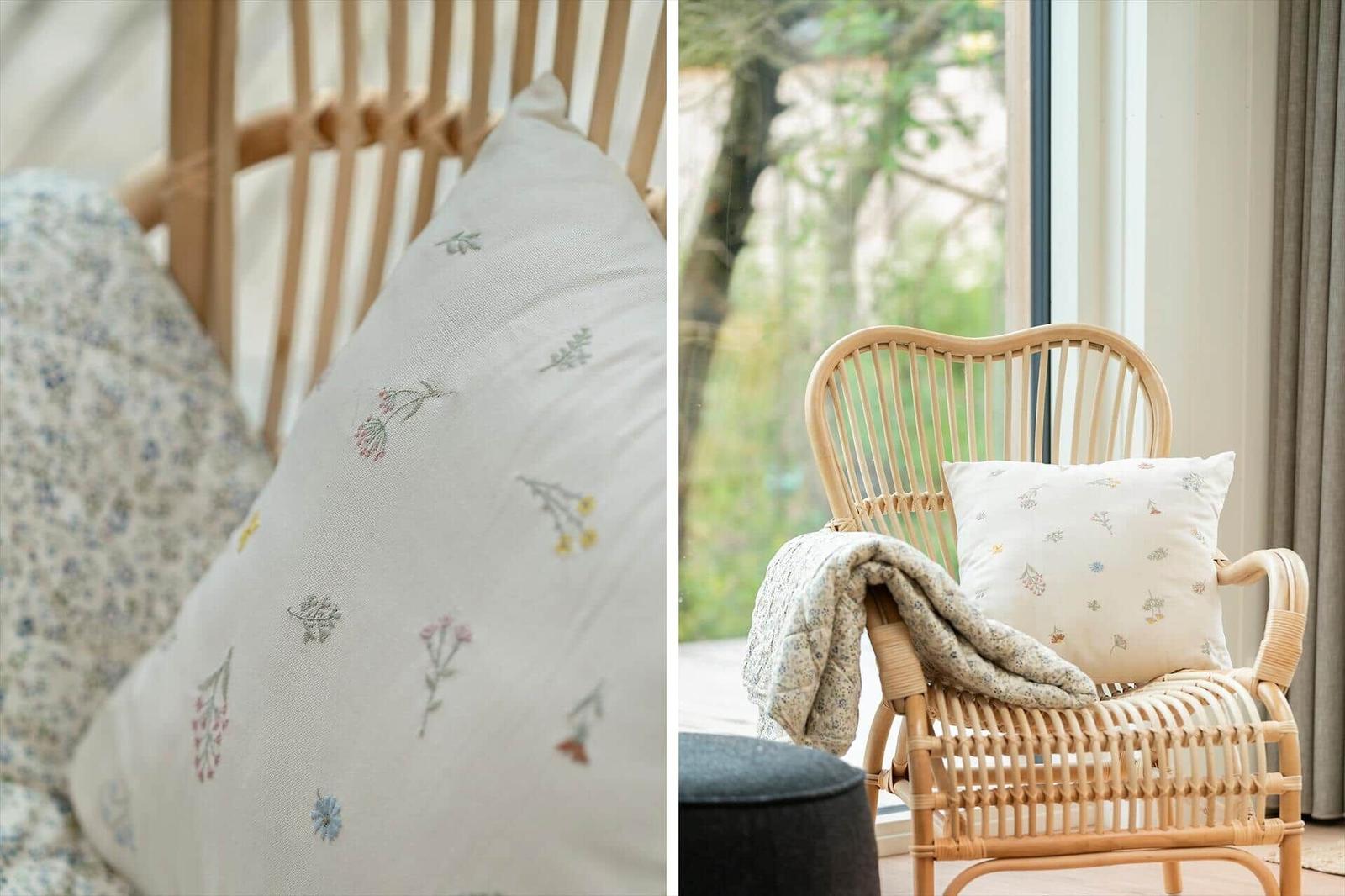 Rattan-Stuhl mit Kissen und Decke vor großem Fenster