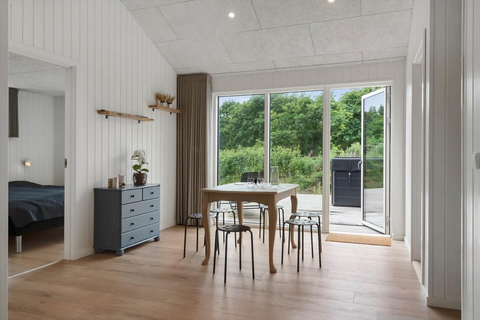 Essbereich mit Tisch und Stühlen, Blick auf Garten durch große Glastüren.