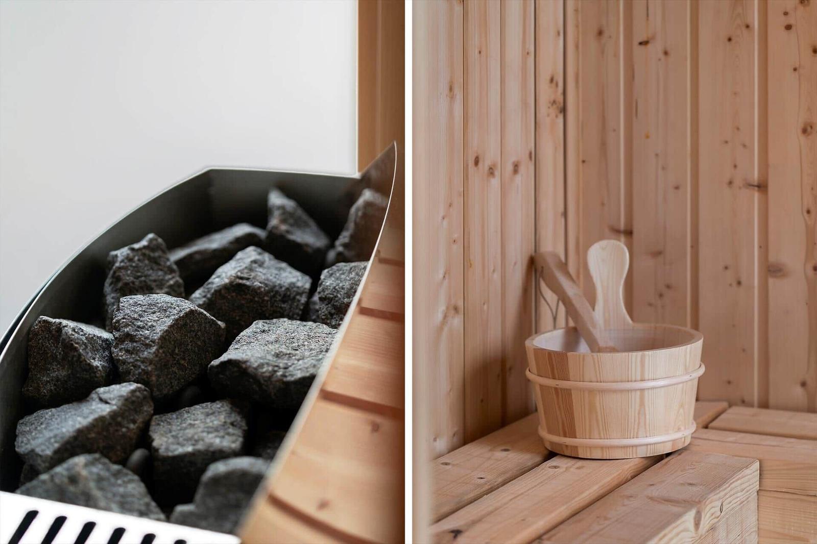 Sauna mit Holzbank und Eimer. Steine im Ofenbereich.