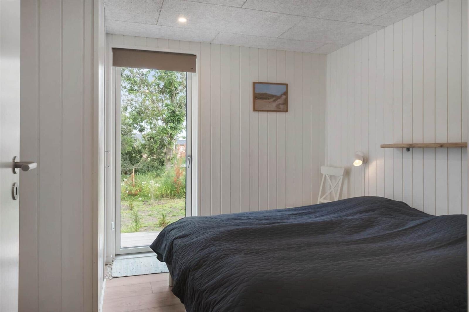 Schlafzimmer mit Bett, Fenster und Wandbild.