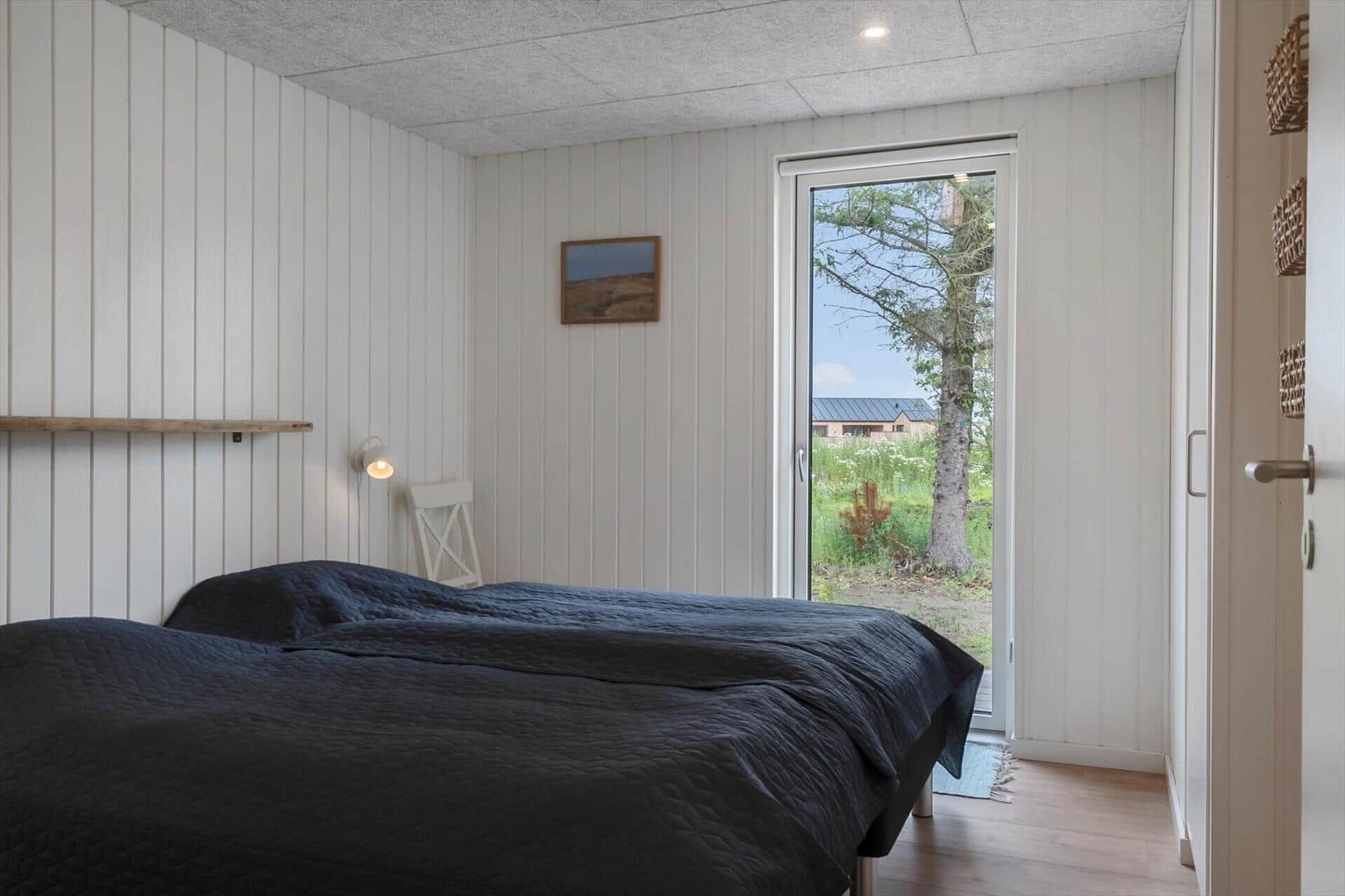Schlafzimmer mit Bett, Tür zum Garten und Wandbild.
