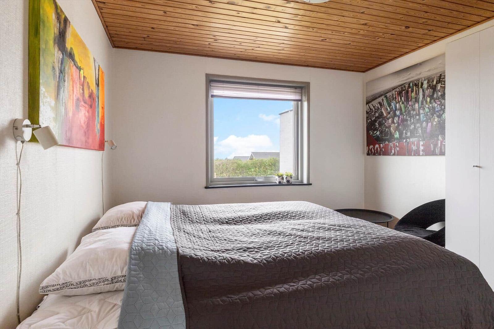Schlafzimmer mit Bett, Fenster und Wandbildern