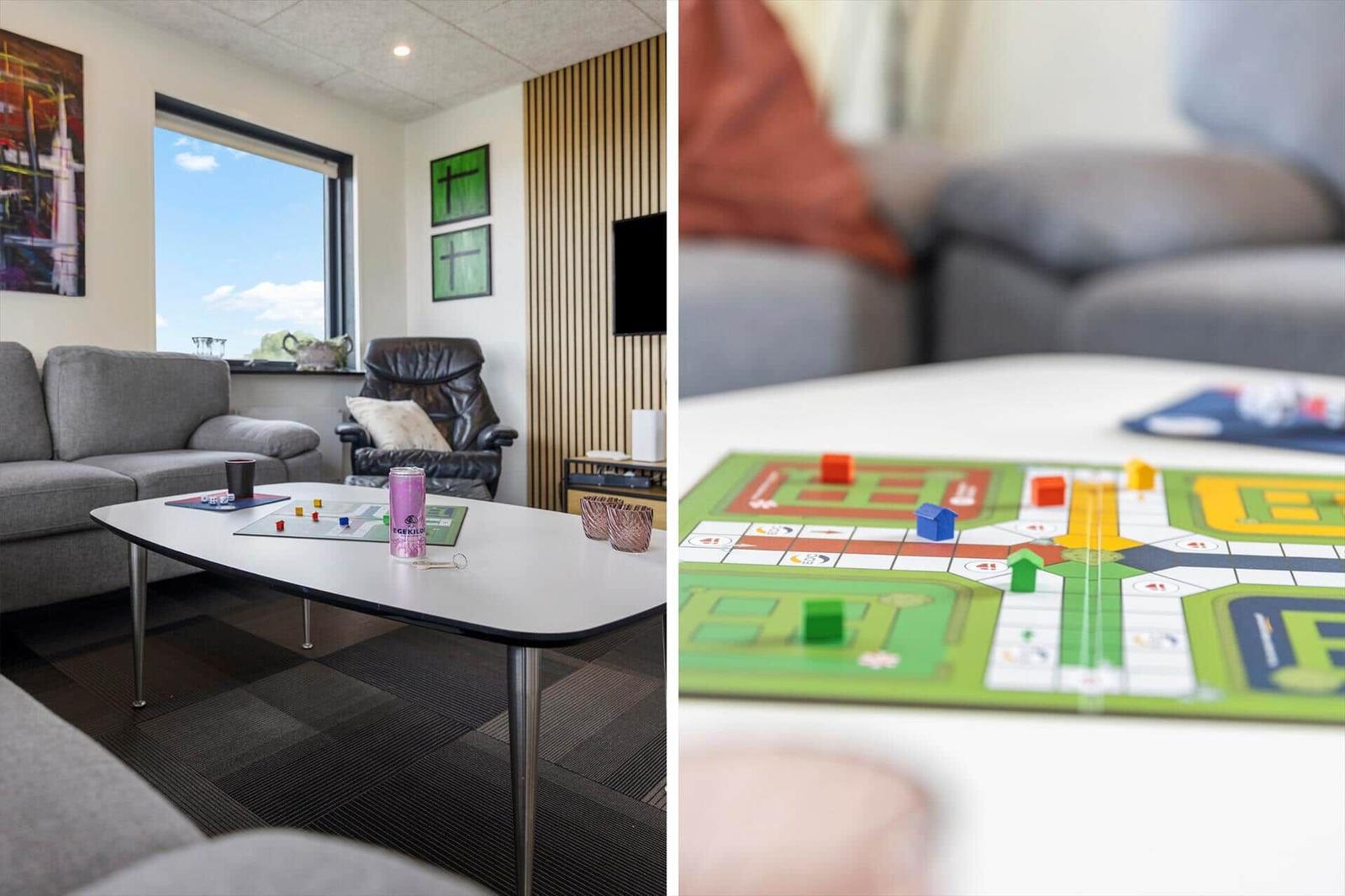 Wohnzimmer mit Sofa, Spielplatte und Fenster. Spielbrett mit Spielsteinen auf Tisch.