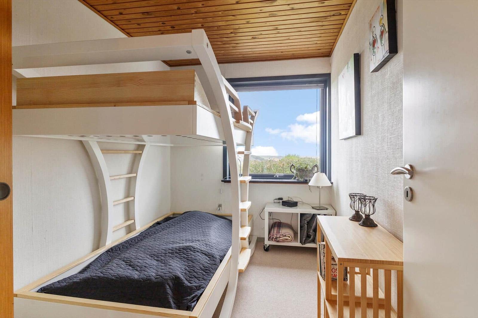 Zimmer mit Doppelstockbett, Fenster mit Aussicht und Schreibtisch.