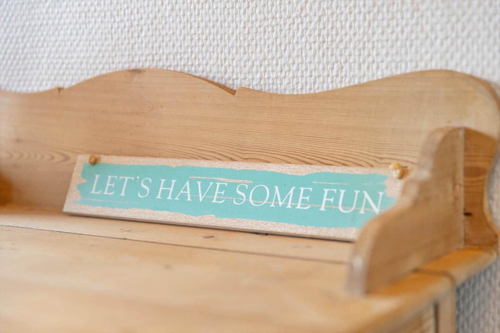 Holzbank mit Schild: LETS HAVE SOME FUN an Wand