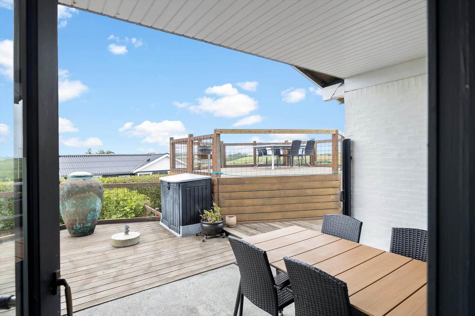 Terrasse mit Tisch, Stühlen und Blick auf grüne Landschaft.