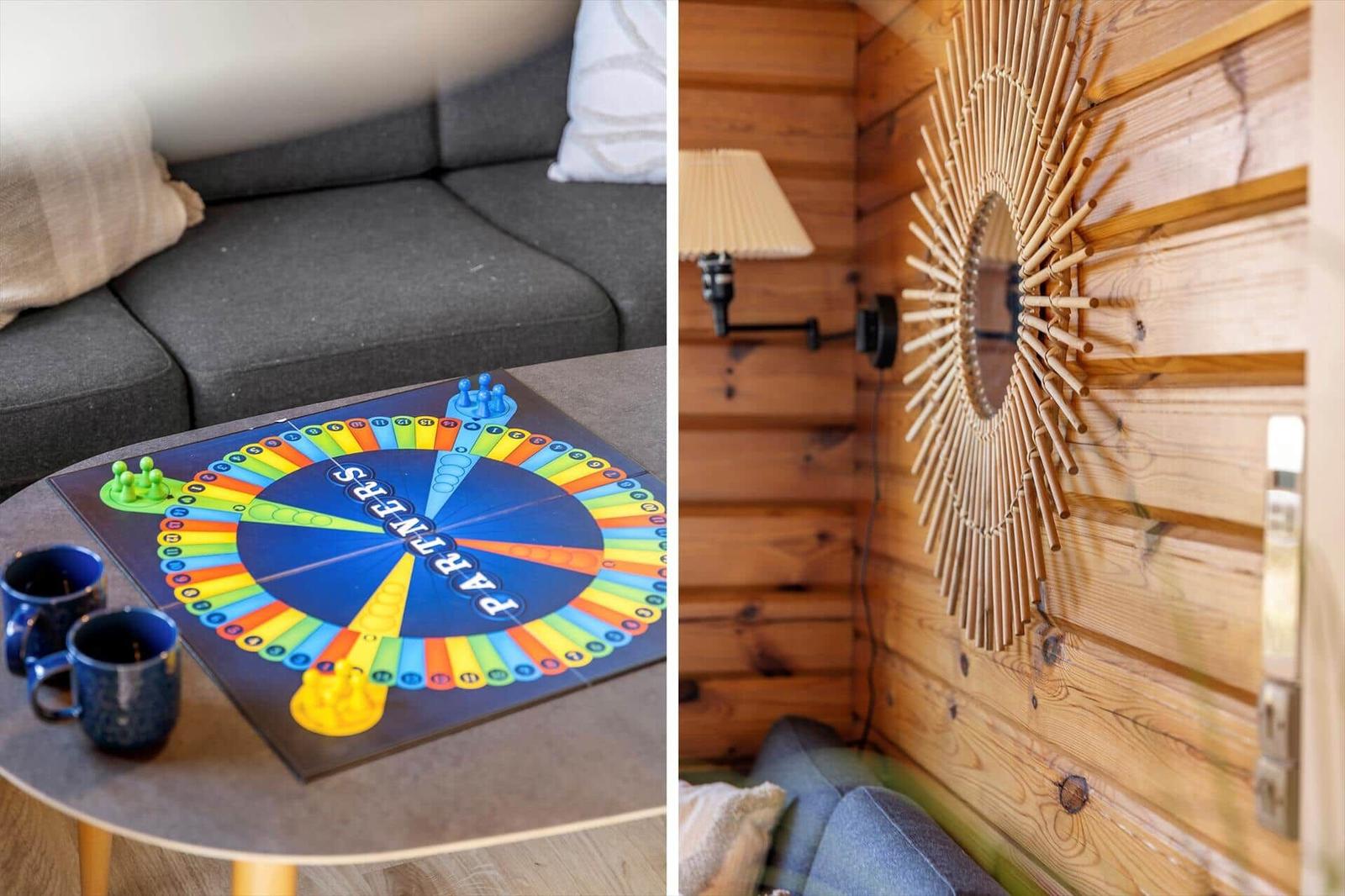 Tisch mit Spiel und Tassen vor Sofa. Wandspiegel mit Bambusrahmen an Holzwand.