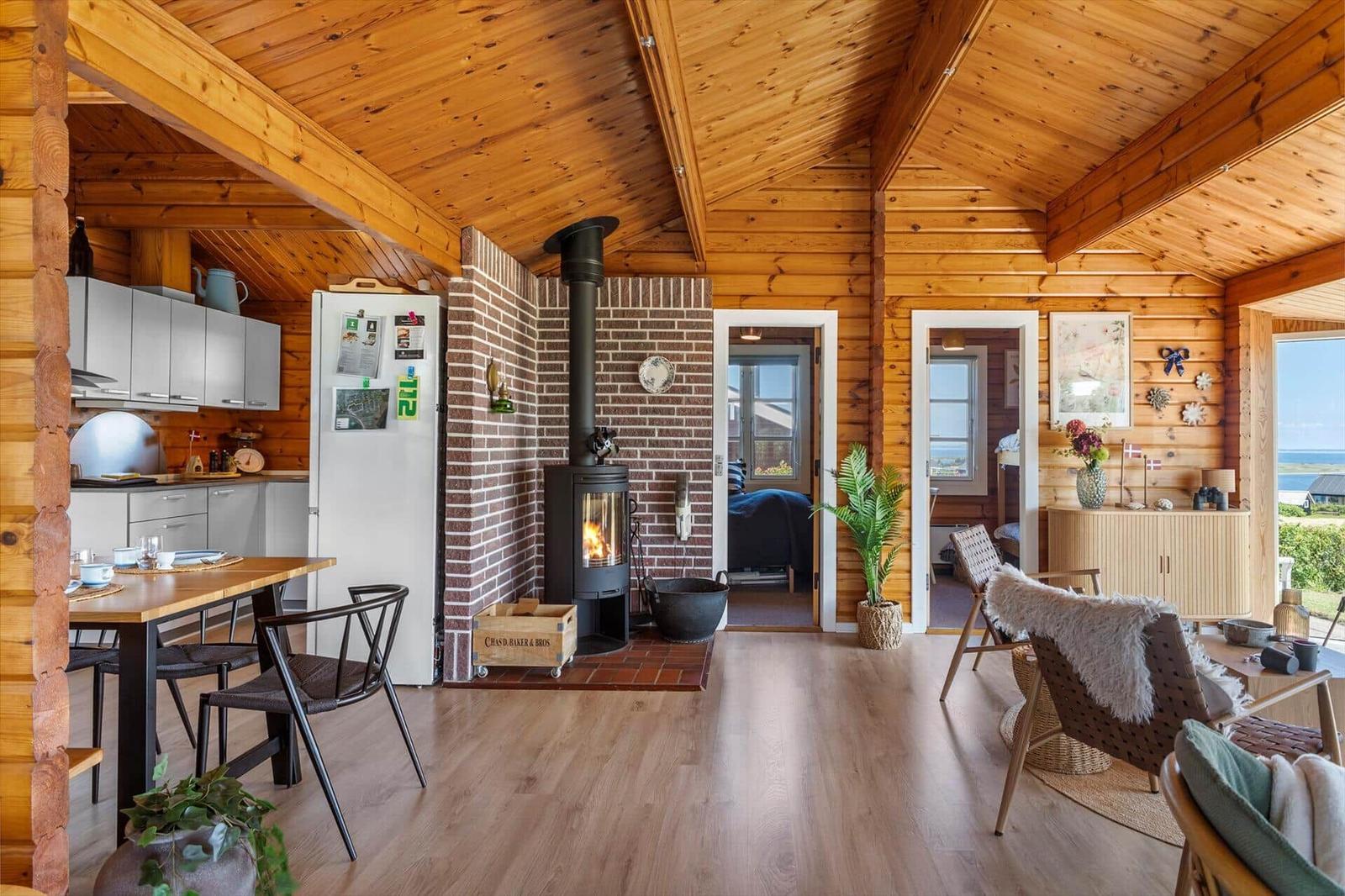 Haus mit Holzdecke, Kamin, Küche und Wohnbereich mit Blick aufs Meer.