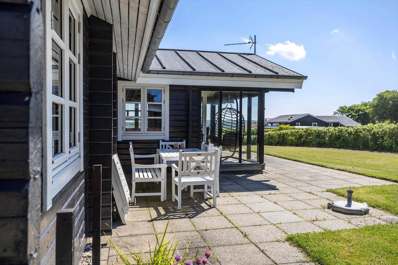Terrasse mit weißem Tisch und Stühlen, Glasveranda und Garten
