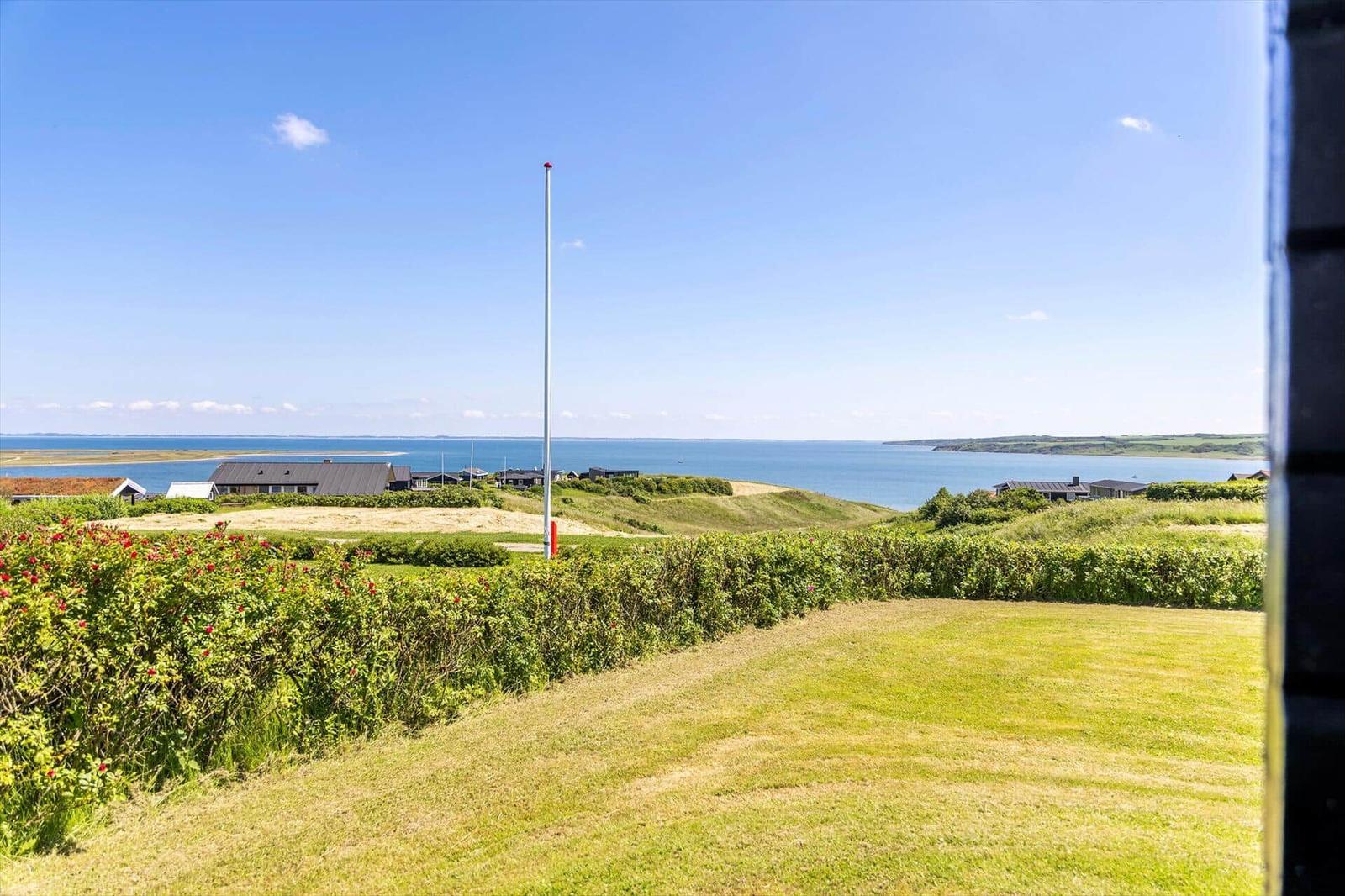 Weitläufiger Blick aufs Meer mit Grünflächen und Häusern im Vordergrund.